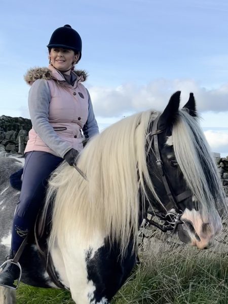 Girl riding cob with body protector on